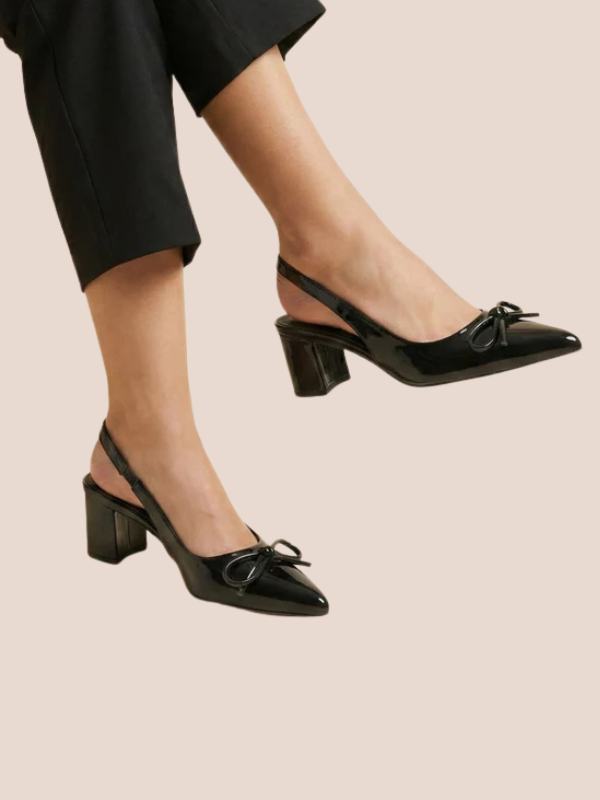 Black Dira Slingback Bow Pumps with glossy patent leather finish, pointed toe design, and adjustable slingback strap, featuring a decorative bow detail at the front, high stiletto heel.