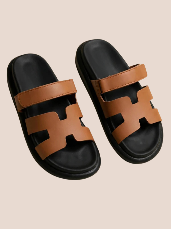 Brown Soft Stride with black soles worn by a person on a beige background.
