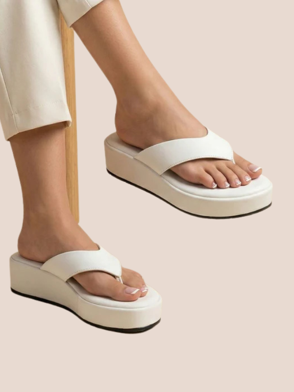 White platform sandals worn by a person on a beige background.