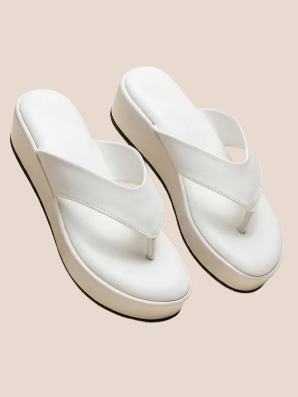 White platform sandals worn by a person on a beige background.