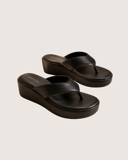 Person wearing beige pants and black sandals on a light background.