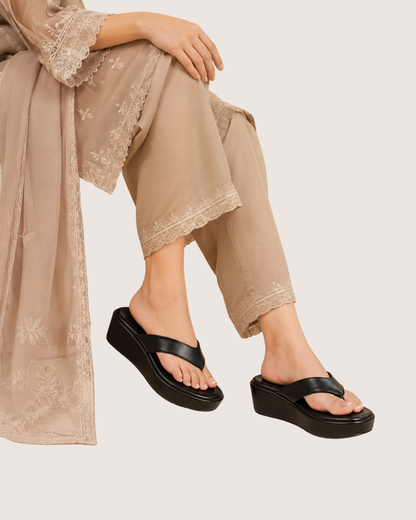 Person wearing beige pants and black sandals on a light background.