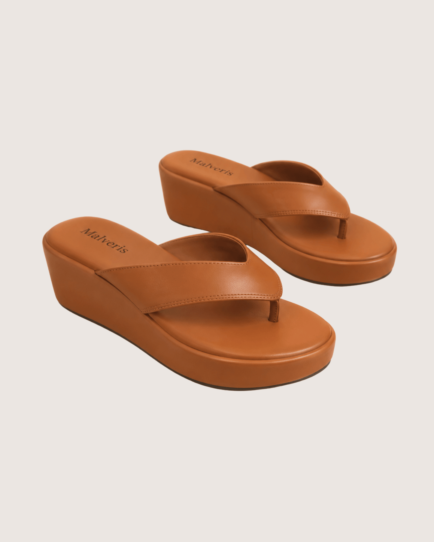 Pair of brown wedge sandals on a beige background.