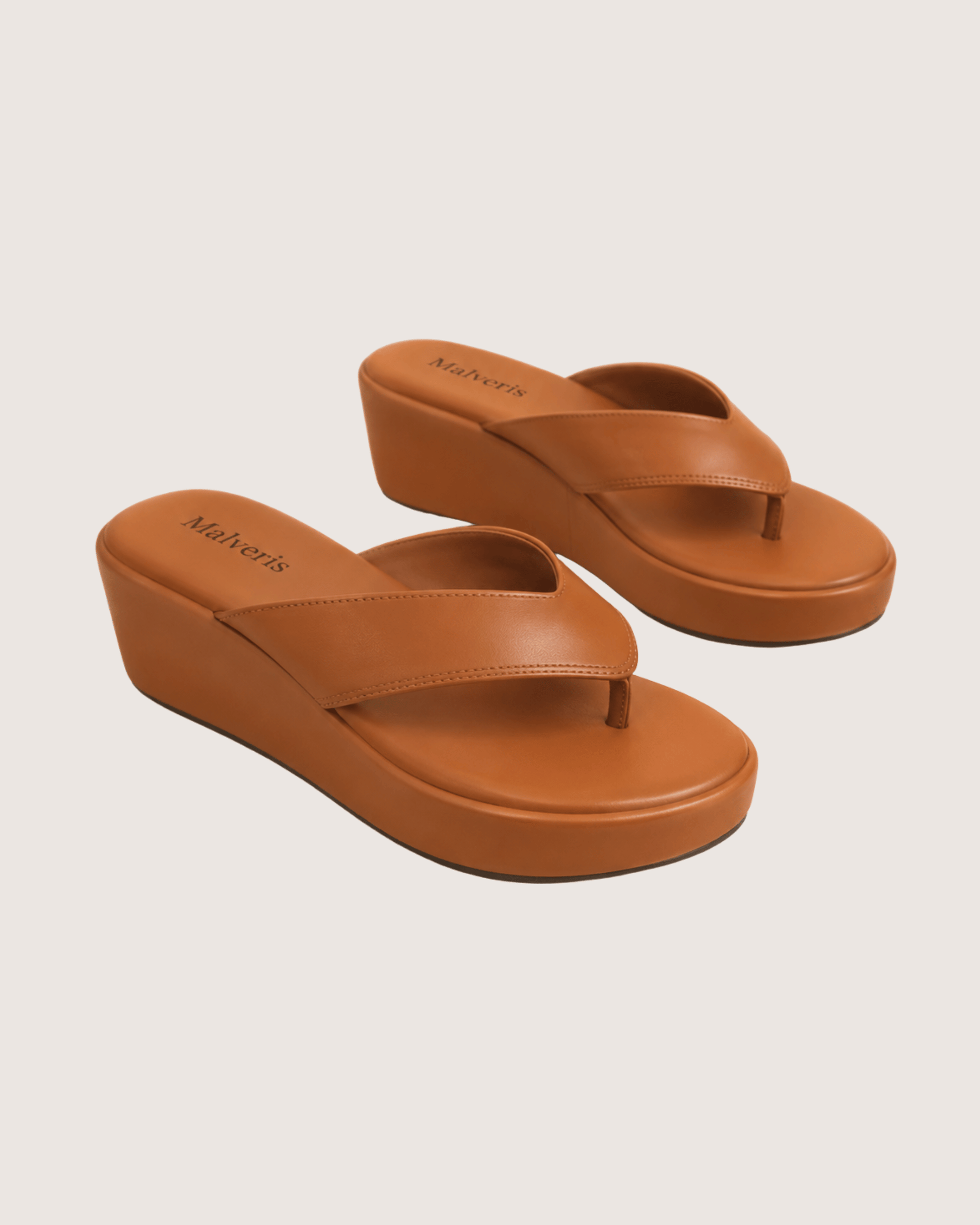 Pair of brown wedge sandals on a beige background.