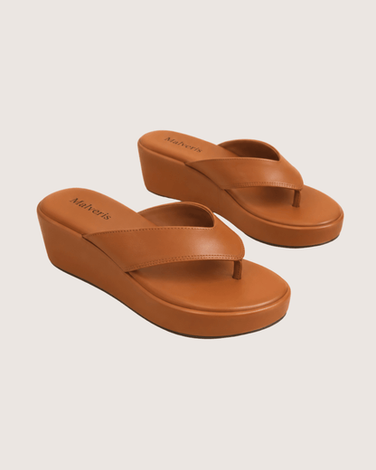 Pair of brown wedge sandals on a beige background.