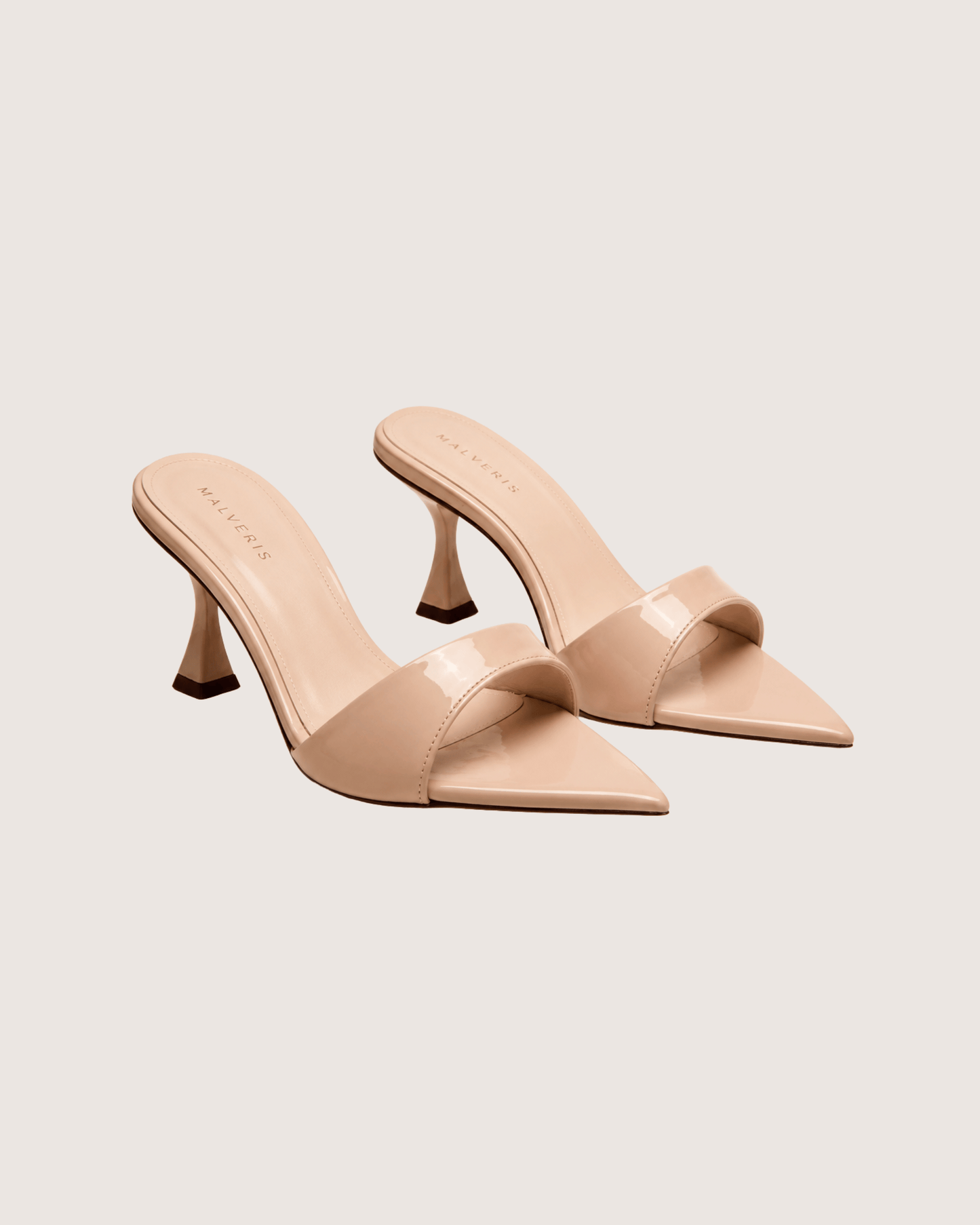 Pair of beige high-heeled mules on a light gray background.