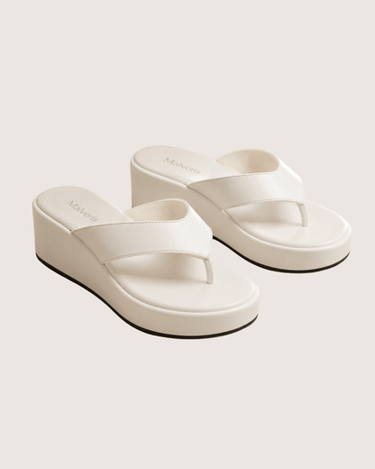 White wedge sandals on a light gray background.